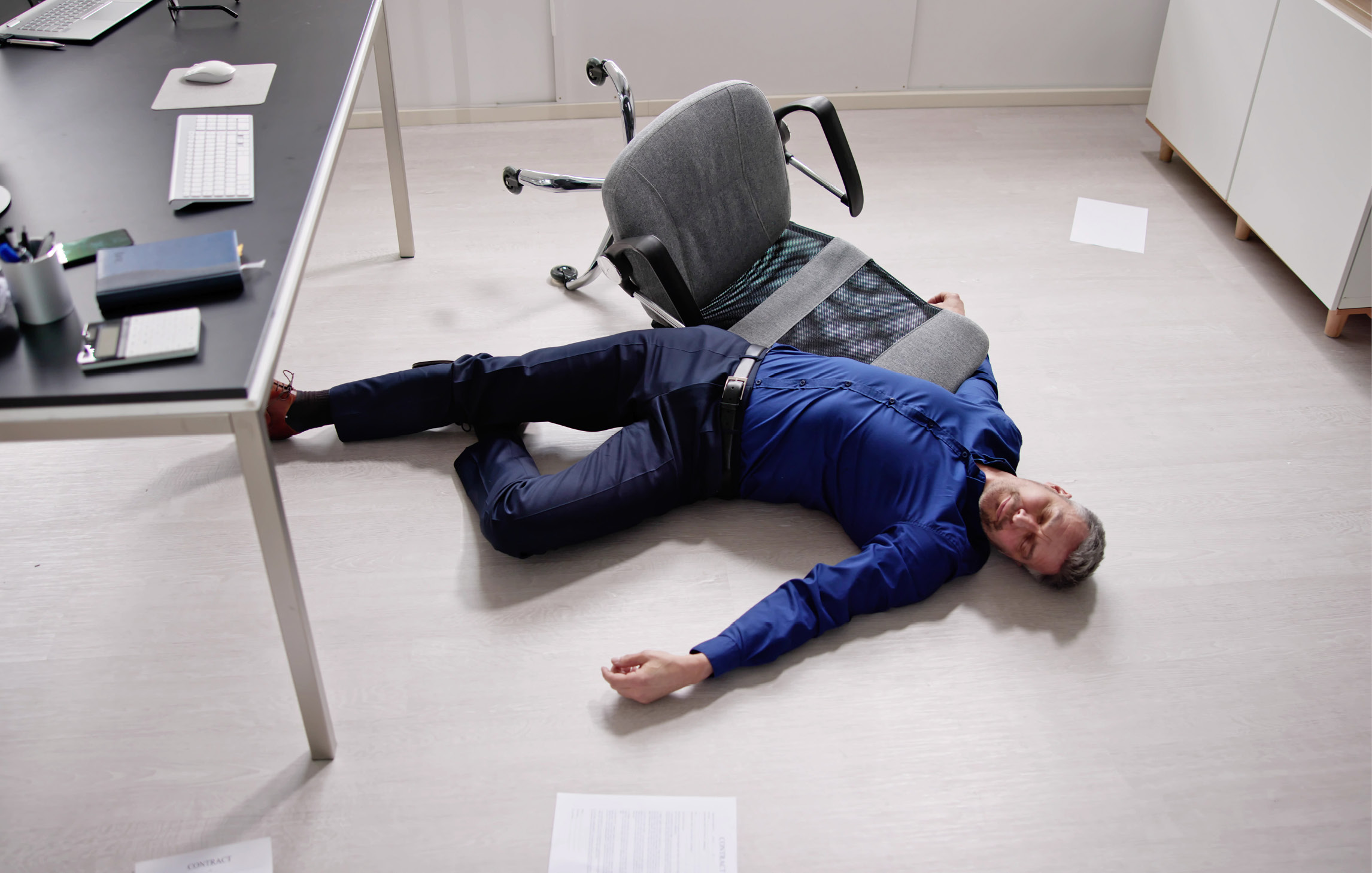 Ein Mann ist in seinem Büro zusammengebrochen und liegt bewusstlos neben seinem Schreibtischstuhl